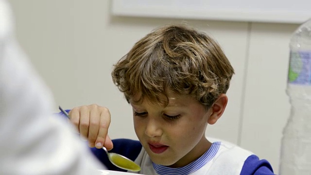 英俊的孩子用勺子喝汤的随意镜头。儿童吃食物4K视频素材