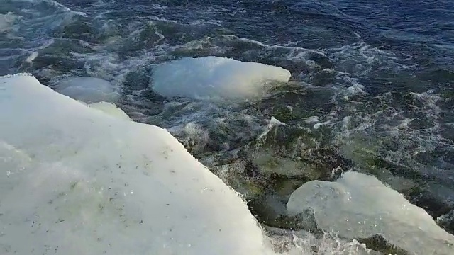 海浪拍打冰面的慢镜头，摄像机沿着海岸移动视频素材