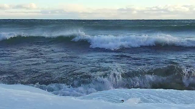 风暴中海浪拍打着覆盖着冰的海岸(慢镜头)视频素材