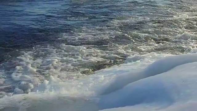 海浪在冰面上破碎这是风暴中的缓慢运动，摄像机沿着海岸的运动视频素材