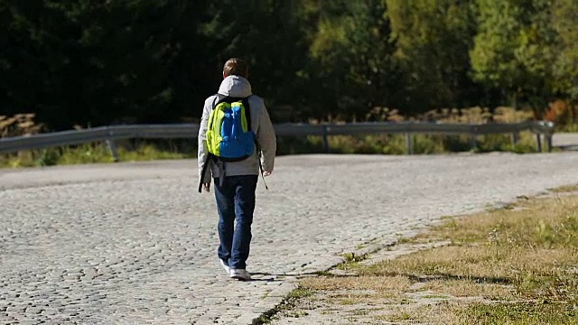 年轻人走在空荡荡的山路上环顾四周，活跃的旅游视频素材