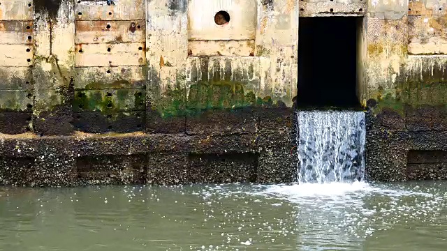 雨后日常生活视频。水从城里的一条运河流向大海。以水浸概念来排水及防止城市水浸。视频素材