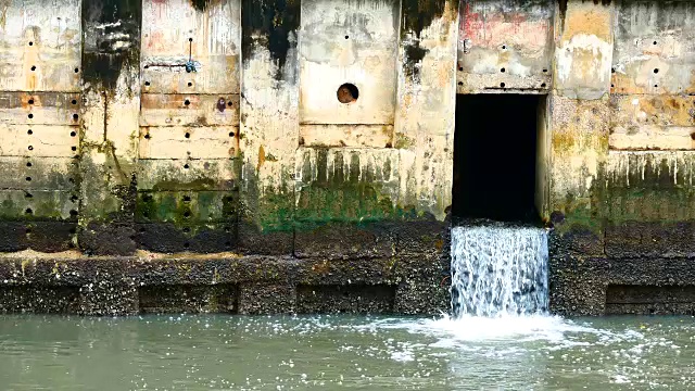 雨后日常生活视频。水从城里的一条运河流向大海。以水浸概念来排水及防止城市水浸。视频素材