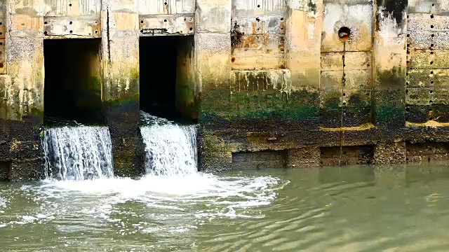 雨后日常生活视频。水从城里的一条运河流向大海。以水浸概念来排水及防止城市水浸。视频素材