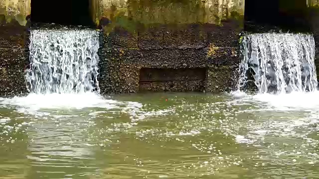 雨后日常生活视频。水从城里的一条运河流向大海。以水浸概念来排水及防止城市水浸。视频素材