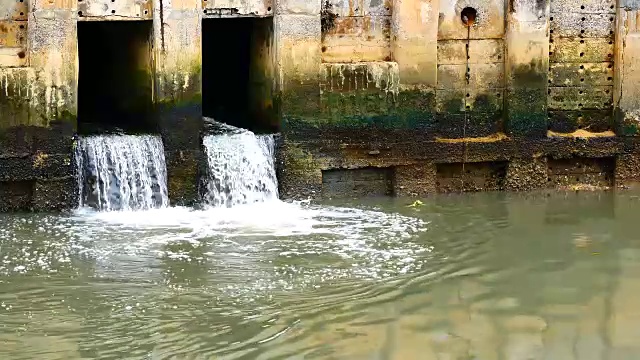 雨后日常生活视频。水从城里的一条运河流向大海。以水浸概念来排水及防止城市水浸。视频素材