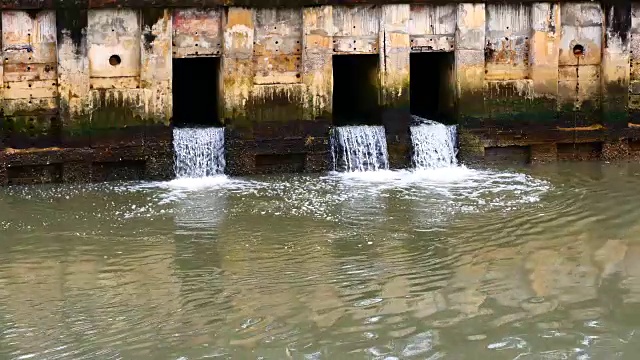 雨后日常生活视频。水从城里的一条运河流向大海。以水浸概念来排水及防止城市水浸。视频素材