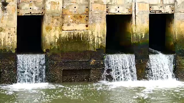 雨后日常生活视频。水从城里的一条运河流向大海。以水浸概念来排水及防止城市水浸。视频素材