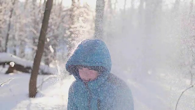 一个孩子在冬天的户外玩耍，奔跑，把雪扔到山顶。积极的户外运动视频素材