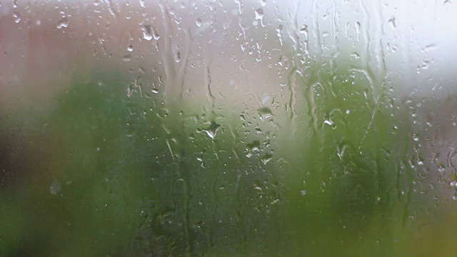 雨和水滴落在玻璃上在暴雨，近距离。视频素材