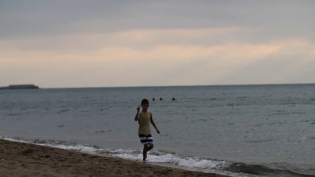 在美丽的夜空下，梦想的男孩乘着一架纸飞机沿着海岸奔跑视频素材