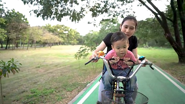 妈妈和小男孩一起在户外公园骑车。视频素材