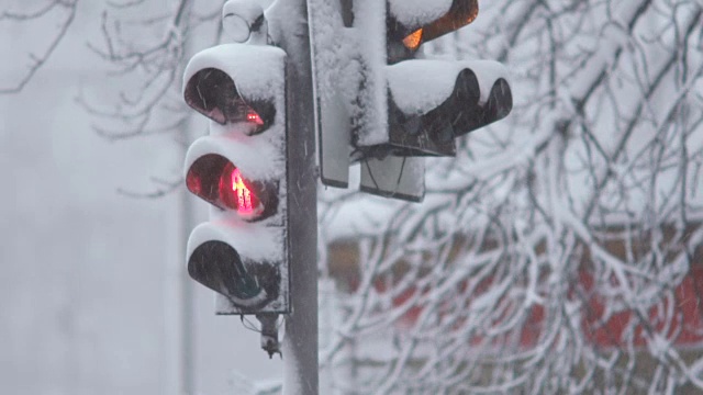 暴风雪期间，雪中的红绿灯控制交通。龙卷风来临时，大雪使道路上汽车的行驶变得复杂。特写镜头视频素材