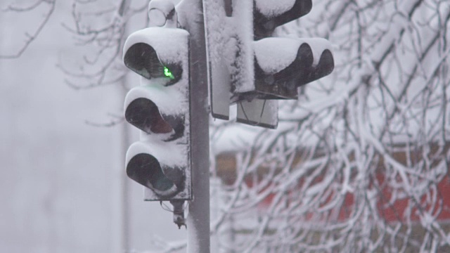 暴风雪期间，雪中的红绿灯控制交通。龙卷风来临时，大雪使道路上汽车的行驶变得复杂。特写镜头视频素材