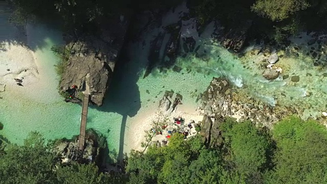 空中俯瞰:游客从木桥上跳入清澈的河水中视频素材