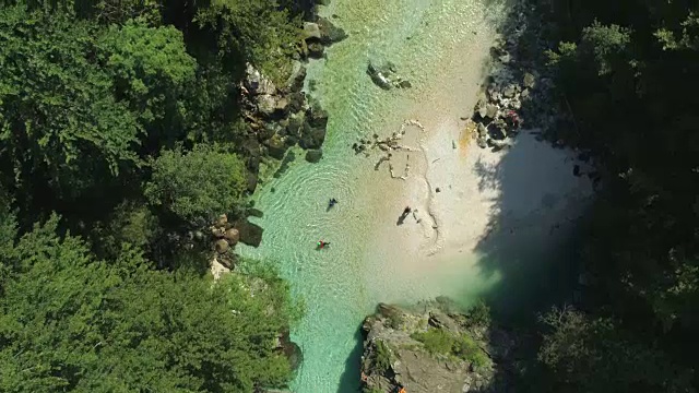 空中俯瞰:在阳光普照的夏日，人们跳入碧绿的河流中。视频素材