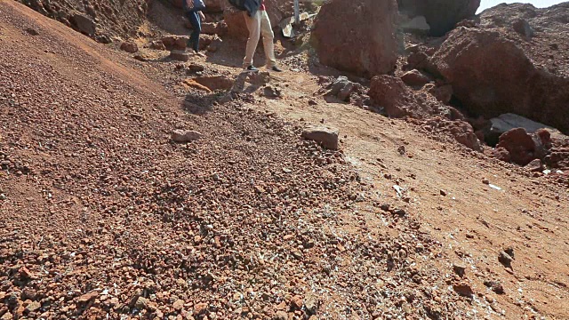 许多游客沿着火山起源的山脉的危险斜坡行走视频素材