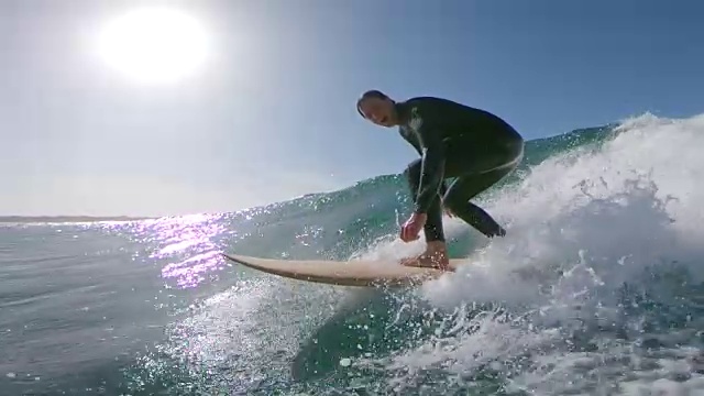 慢镜头，镜头光晕:兴奋的冲浪运动员微笑着，骑着波浪向海岸走去。视频素材