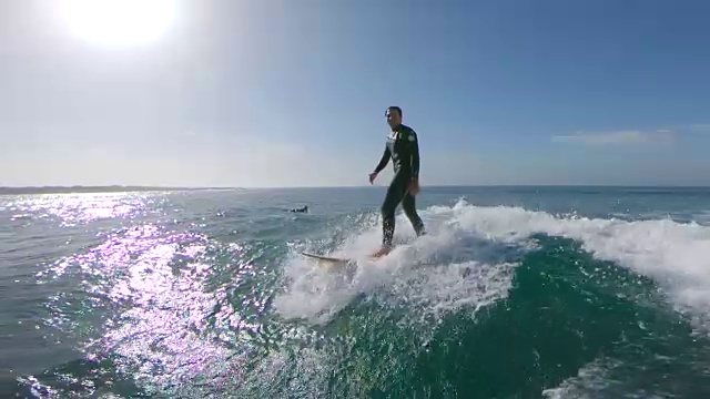 慢镜头，镜头光晕:快乐的男性冲浪者骑在波浪和跳进水里。视频素材