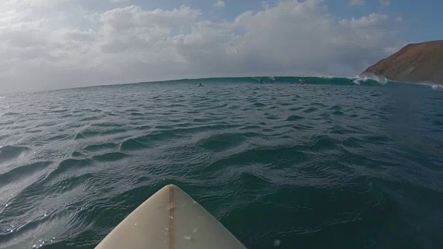 慢动作POV:年轻的冲浪者在他的冲浪板上划桨，排成一行，抓住海浪视频素材