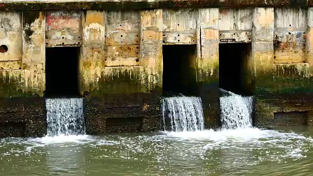 雨后日常生活视频。水从城里的一条运河流向大海。以水浸概念来排水及防止城市水浸。视频素材