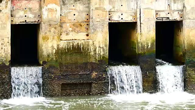 雨后日常生活视频。水从城里的一条运河流向大海。以水浸概念来排水及防止城市水浸。视频素材