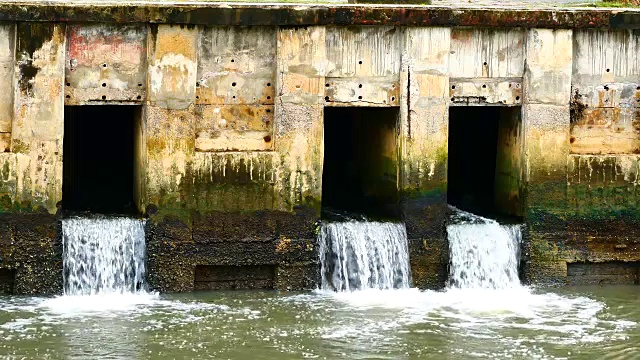 雨后日常生活视频。水从城里的一条运河流向大海。以水浸概念来排水及防止城市水浸。视频素材