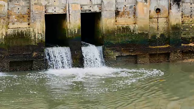 雨后日常生活视频。水从城里的一条运河流向大海。以水浸概念来排水及防止城市水浸。视频素材