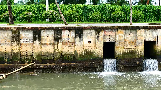 雨后日常生活视频。水从城里的一条运河流向大海。以水浸概念来排水及防止城市水浸。视频素材