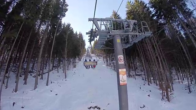 滑雪缆车载着人们上山，滑雪者从雪山上下来，人们在滑雪，高山上的云杉，晴天，从第一个人视频素材