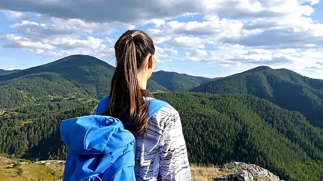 女人背着背包在山顶看日落，徒步女孩庆祝生活，风景优美的自然景观，享受假期旅行冒险视频素材