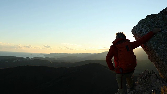 一个成熟的登山者停下来从山脊眺望海景视频素材