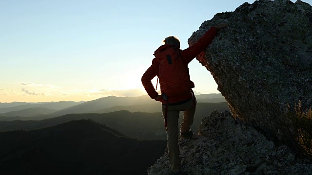 一个成熟的登山者停下来从山脊眺望海景视频素材