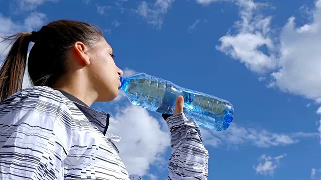 低角度观看女子饮水在山顶的日落徒步女孩庆祝生活风景自然景观享受度假旅行冒险，4k视频素材