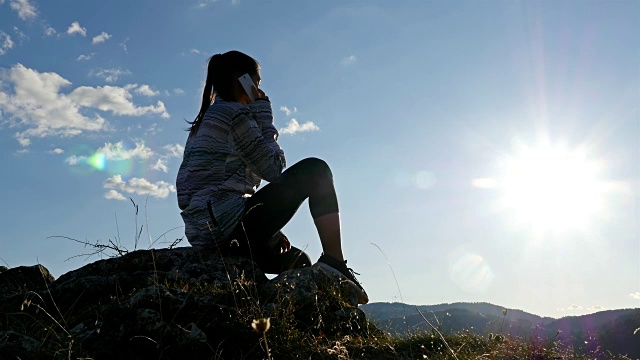 女徒步旅行者女孩带着手机在山顶的日落景区享受自然景观度假旅行探险，4k视频素材