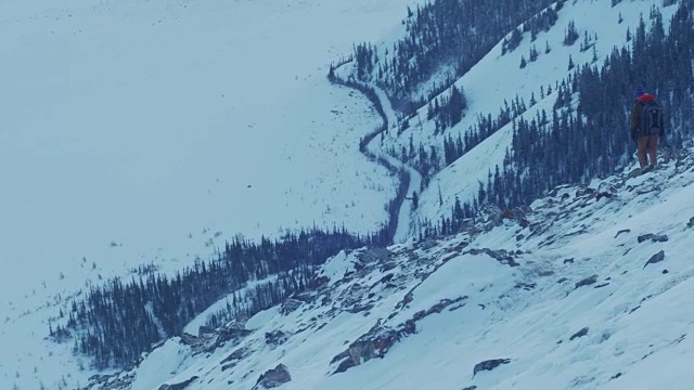 一个徒步旅行者从一座崎岖多雪的山上下来视频素材