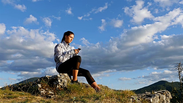 女徒步旅行者女孩在山顶上用手机打字在日落风景优美的自然景观享受度假旅行冒险，4k视频素材