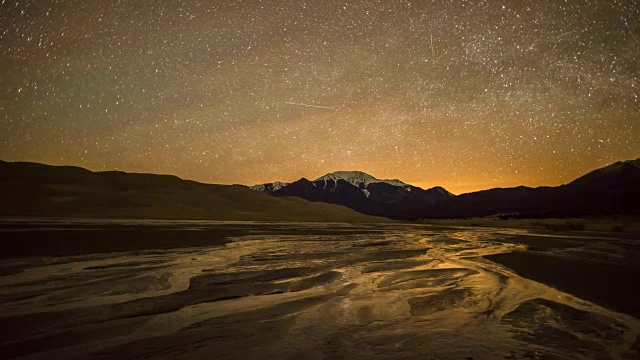 旋转的星空在春天的Medano溪，雪顶的山峰，和沙丘在大沙丘国家公园和保护，科罗拉多州，美国。视频素材