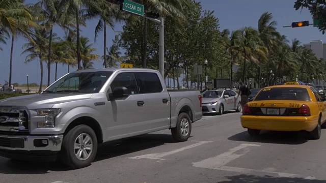 一辆黄色的出租车经过一辆黄色和白色的经典车，在海洋大道上，南海滩，迈阿密，佛罗里达，美国，北美视频素材