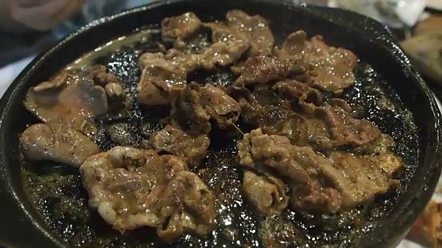 用筷子把烤好的猪肉片、牛肉放在热锅上，配上黄油，在泰国自助烧烤餐厅吃视频下载