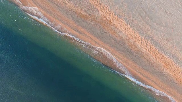 鸟瞰图:清晨海浪冲进荒芜的海滩，俯视图视频素材