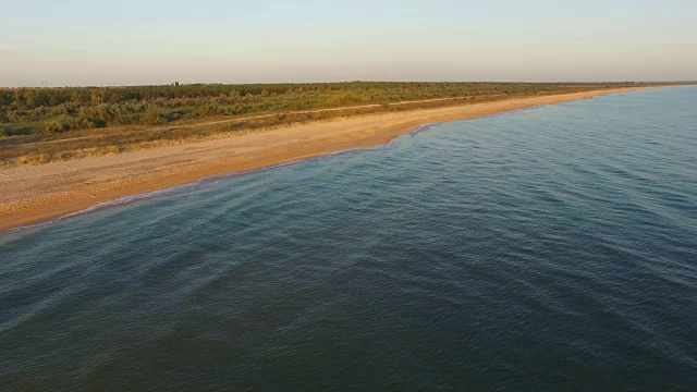 天线:日出时海浪冲进荒芜的海滩视频素材