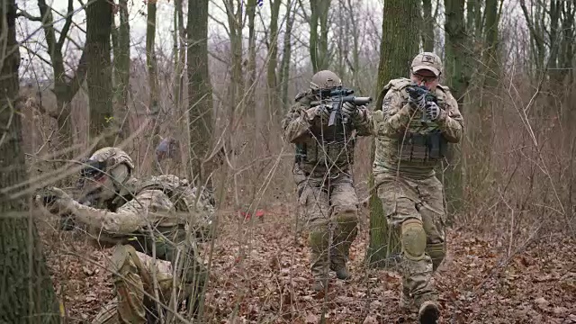 一群年轻的武装士兵在一个地区的武装冲突中穿着制服以突击步枪瞄准森林，慢镜头，软式视频素材