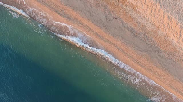 鸟瞰图:黎明时分海浪冲进荒芜的海滩，俯视图视频素材