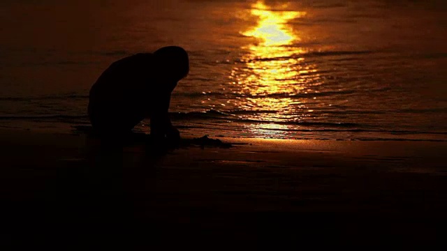 男孩在海浪中嬉戏。夕阳在海浪中倒映。普吉岛,泰国视频素材