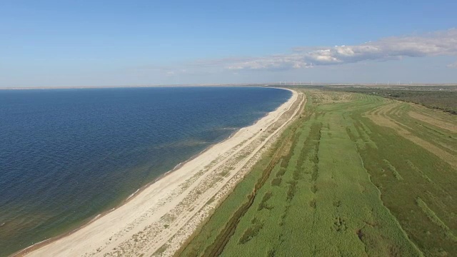 航拍图:蓝色海湾，海岸线沙质，植被繁茂视频素材