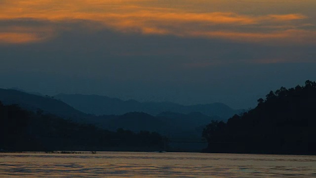 美丽的日落和戏剧性的天空在湖与山脉为背景的泰国。视频素材