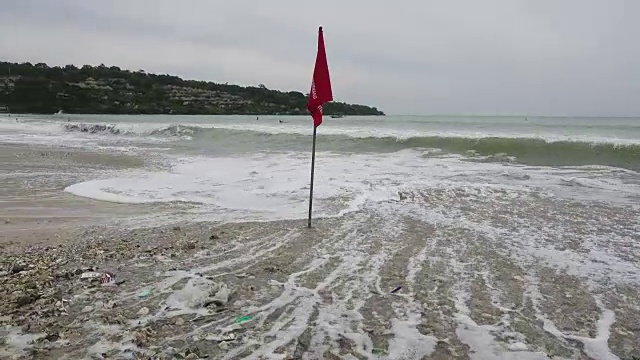 红旗警告，禁止在海滩游泳。因为海浪很大。大浪在海岸上涌动。Jimbaran,巴厘岛视频素材