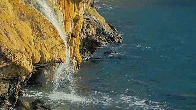 慢镜头:山间瀑布缓缓流入海景。视频素材