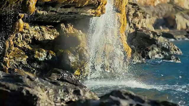 瀑布从天然矿泉水缓缓地流入大海。视频素材